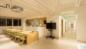 A conference room with a long table, chairs, a TV, and a map on the wall. - Phoenix Egg Youth Hostel (Zhuhai)