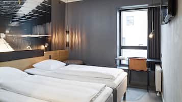 Habitación de hotel moderna con dos camas, un escritorio y un ventanal amplio.