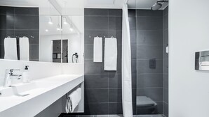 A modern bathroom with a white sink, mirror, and shower curtain.