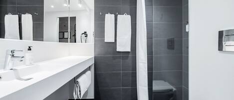A modern bathroom with a white sink, mirror, and shower curtain.