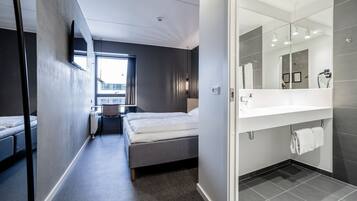 A modern hotel room with a bed, bedside table, and a large mirror.
