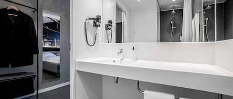 Un baño moderno con un espejo grande, dos lavamanos, una ducha y un perchero para toallas.