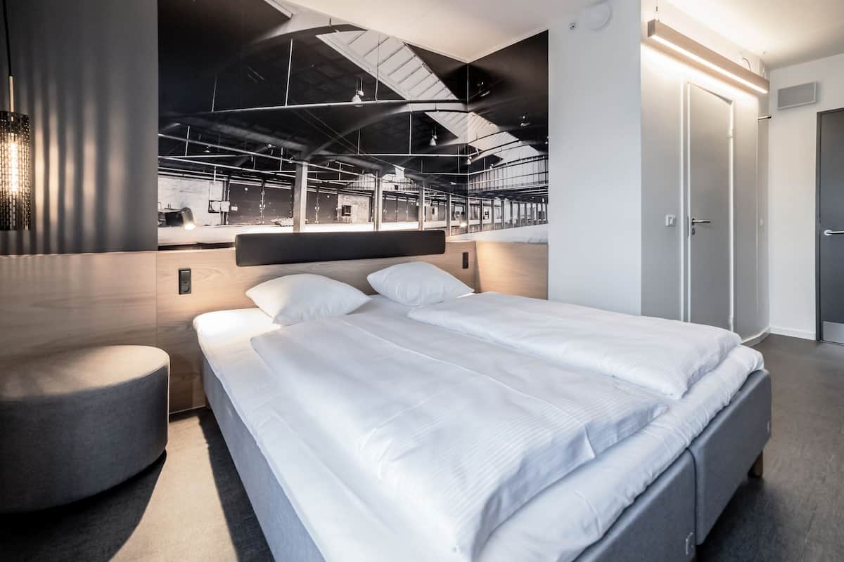 Ein modernes Hotelzimmer mit einem großen Bett, einer Sitzecke und Blick ins Hotelinnere.