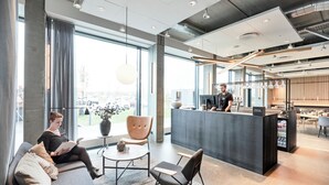 Un área de recepción moderna con bar, asientos y ventanas amplias.