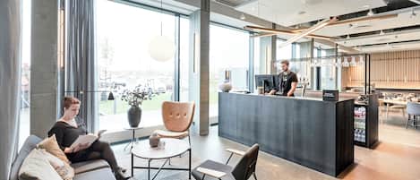 Un área de recepción moderna con bar, asientos y ventanas amplias.