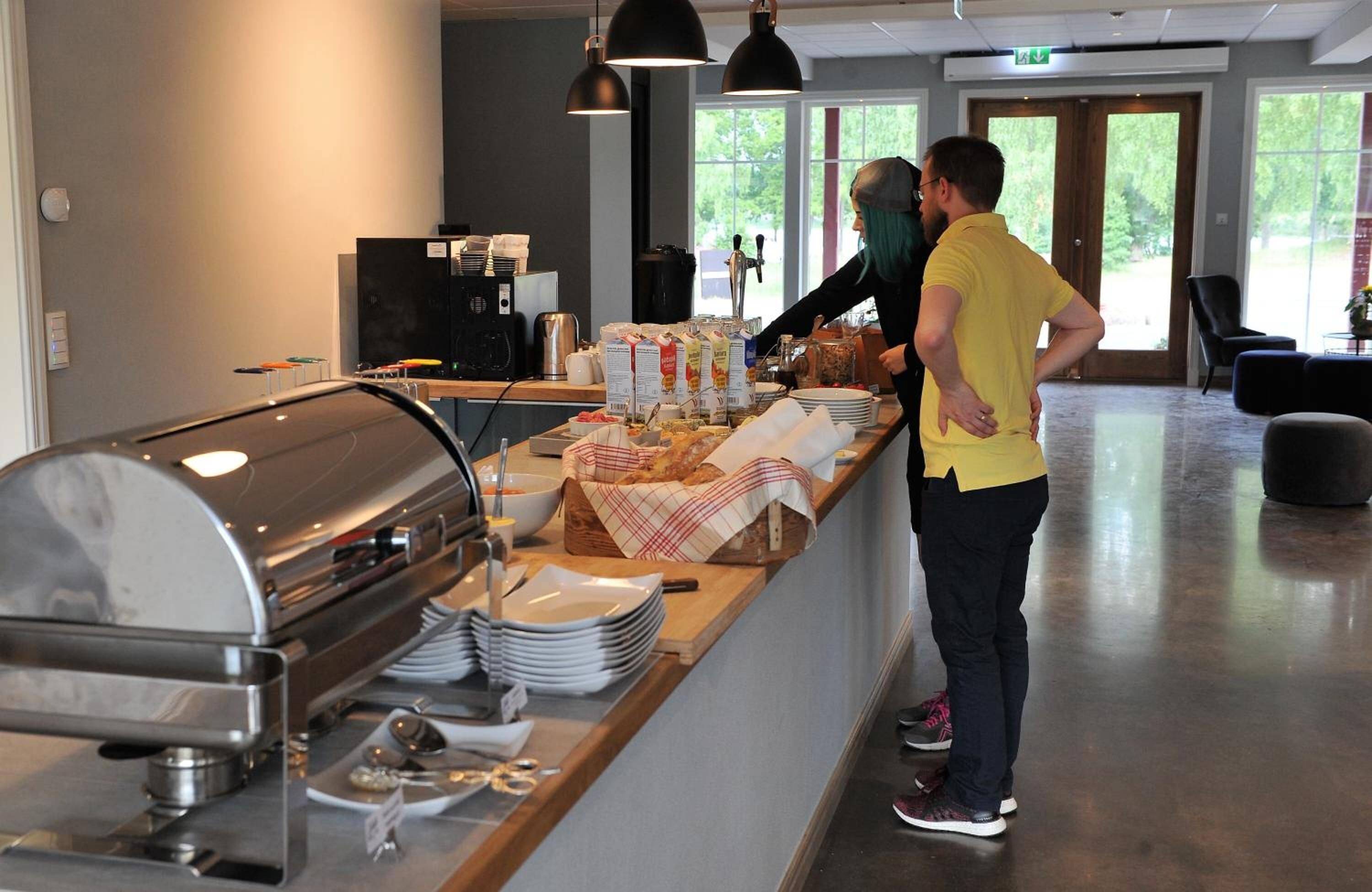 A buffet setup with a grill, plates, and a coffee station.