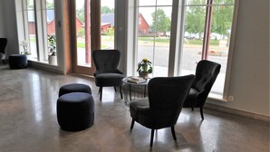 A spacious room with large windows, a round table with a book and a potted plant, and two ottomans.
