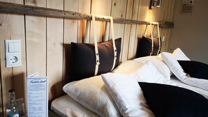 A wooden-paneled room with a bed, pillows, a menu, and a bottle of water.