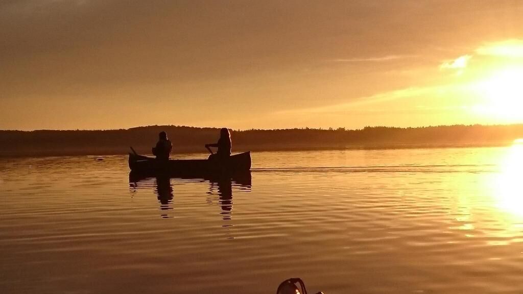 A calm body of water with a boat carrying two people.