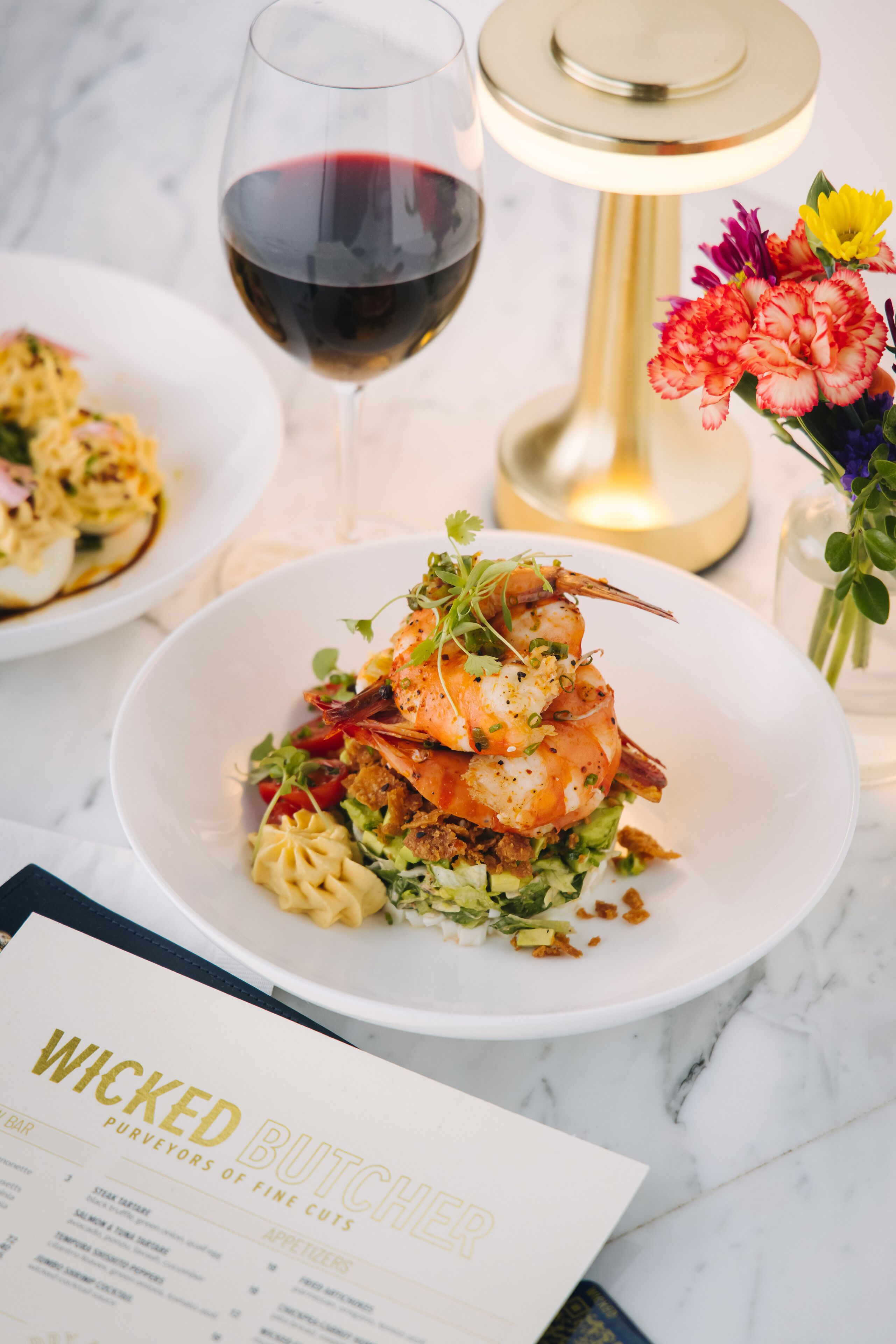 Uma mesa de jantar com um menu intitulado "WICKED BUTCHER" e um prato de comida.