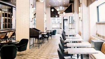 A restaurant with a long counter, black chairs, and a patterned floor.