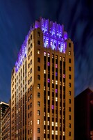 Un edificio moderno a grattacielo, con numerosi piani illuminati da luci viola e gialle.
