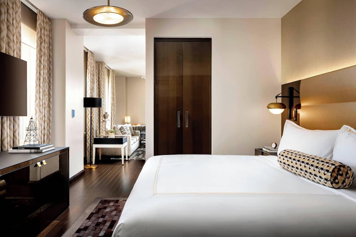 A hotel room with a large bed, a desk, a wardrobe, and a TV.