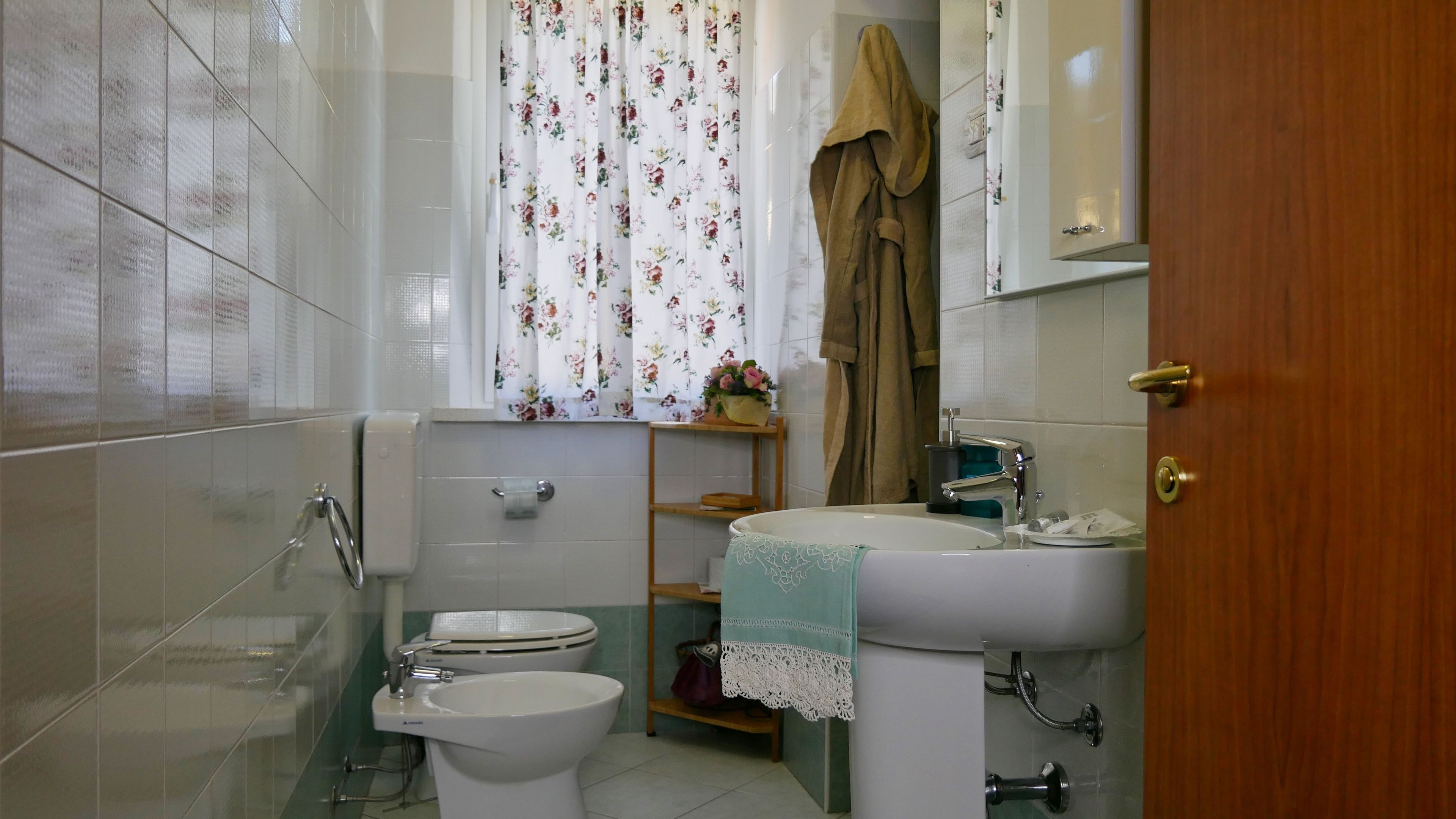 A bathroom with a toilet, bidet, sink, and a shower area.