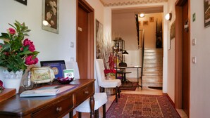 A hallway with a desk, chair, and a rug leading to a staircase.