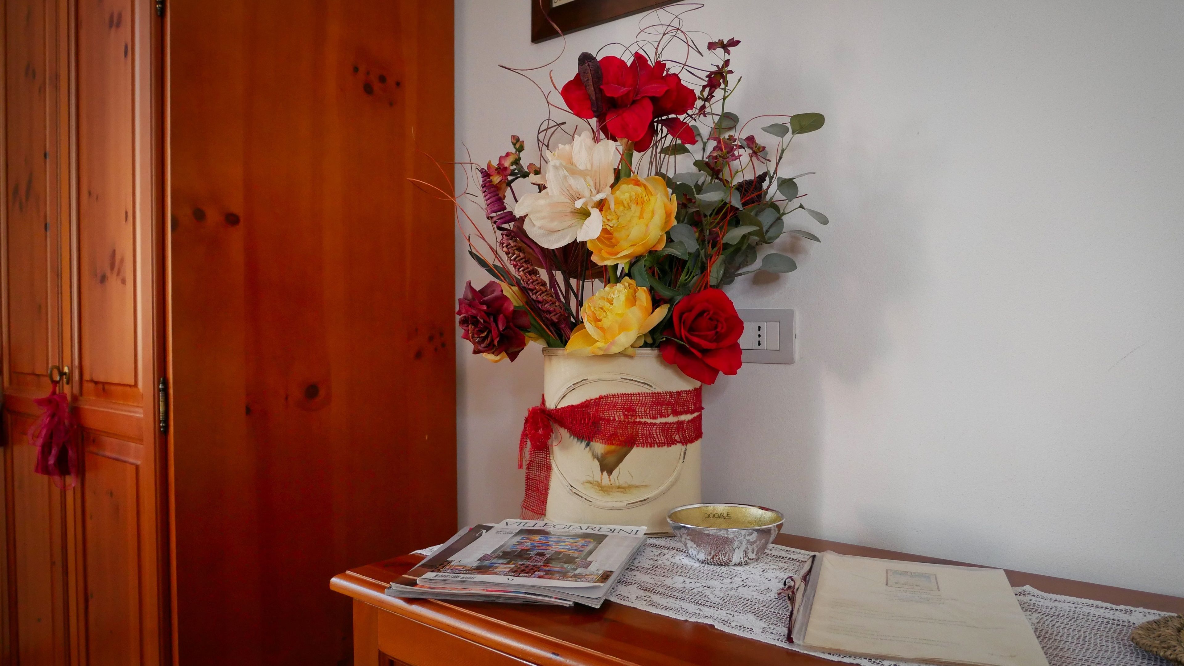 Une porte en bois, un vase avec des fleurs, un journal et un bol sur une table.