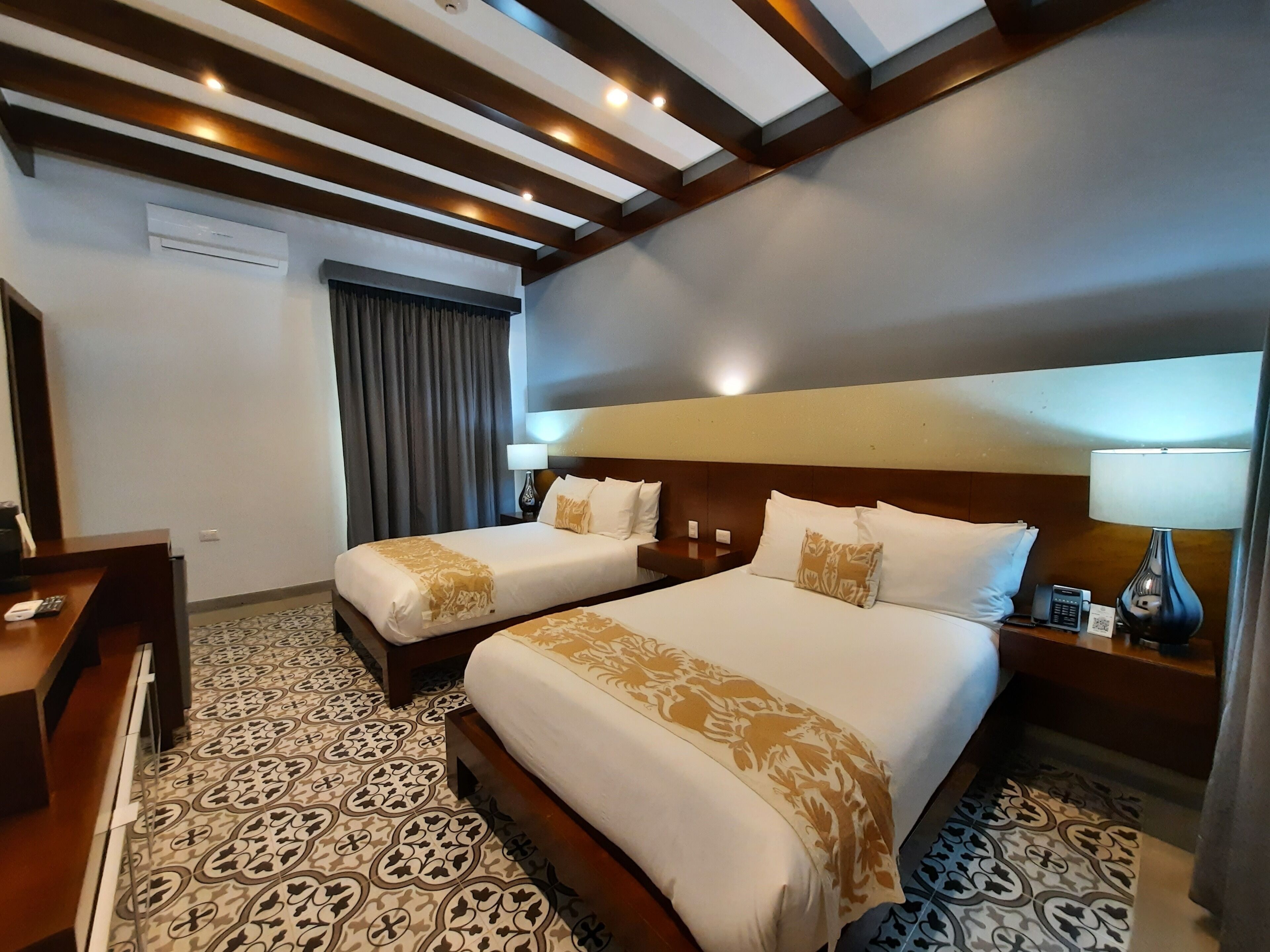 Habitación de hotel con dos camas, un escritorio, un teléfono y una lámpara.