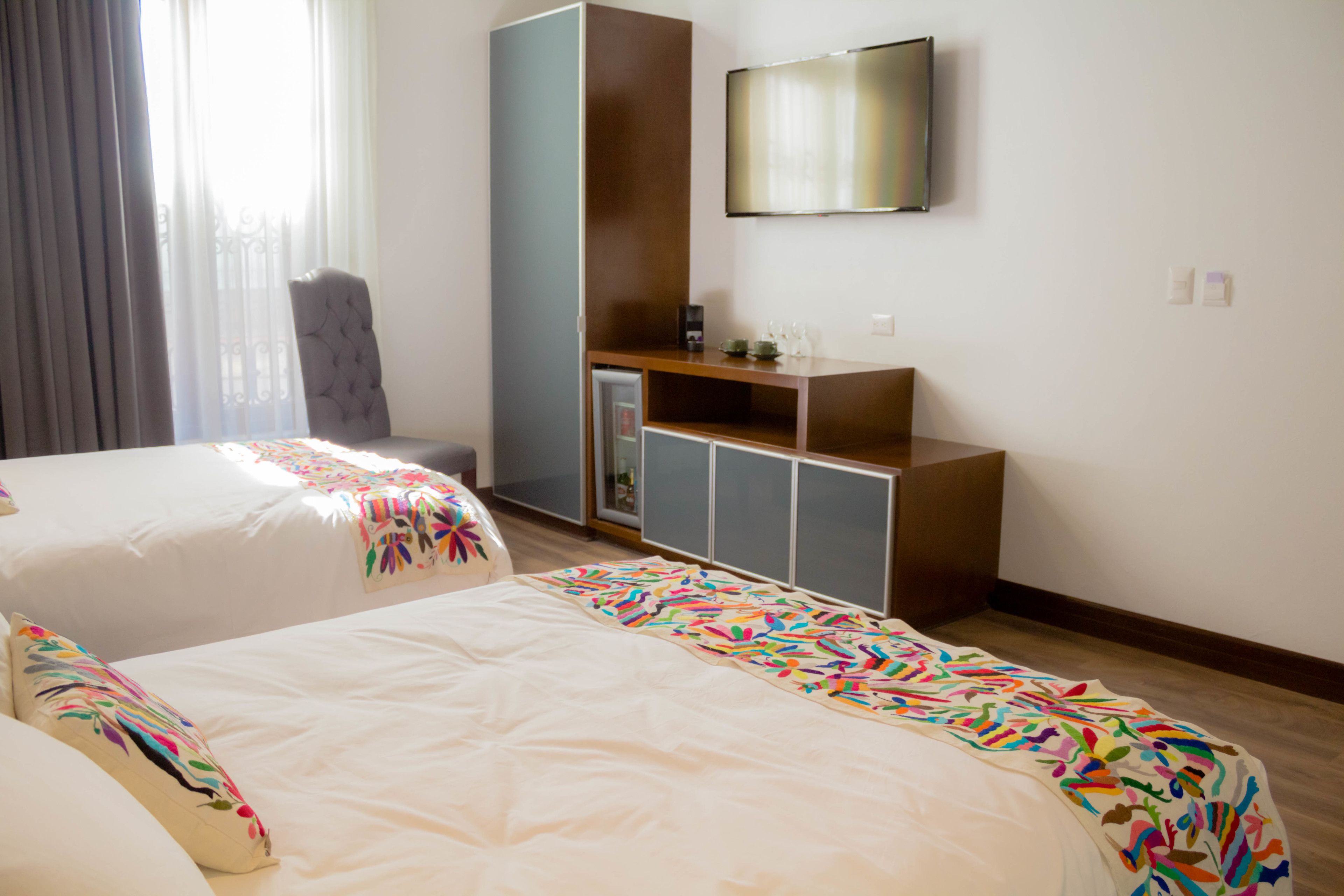 Une chambre d’hôtel avec deux lits, une armoire, une télévision et un bureau équipé d’une machine à café.