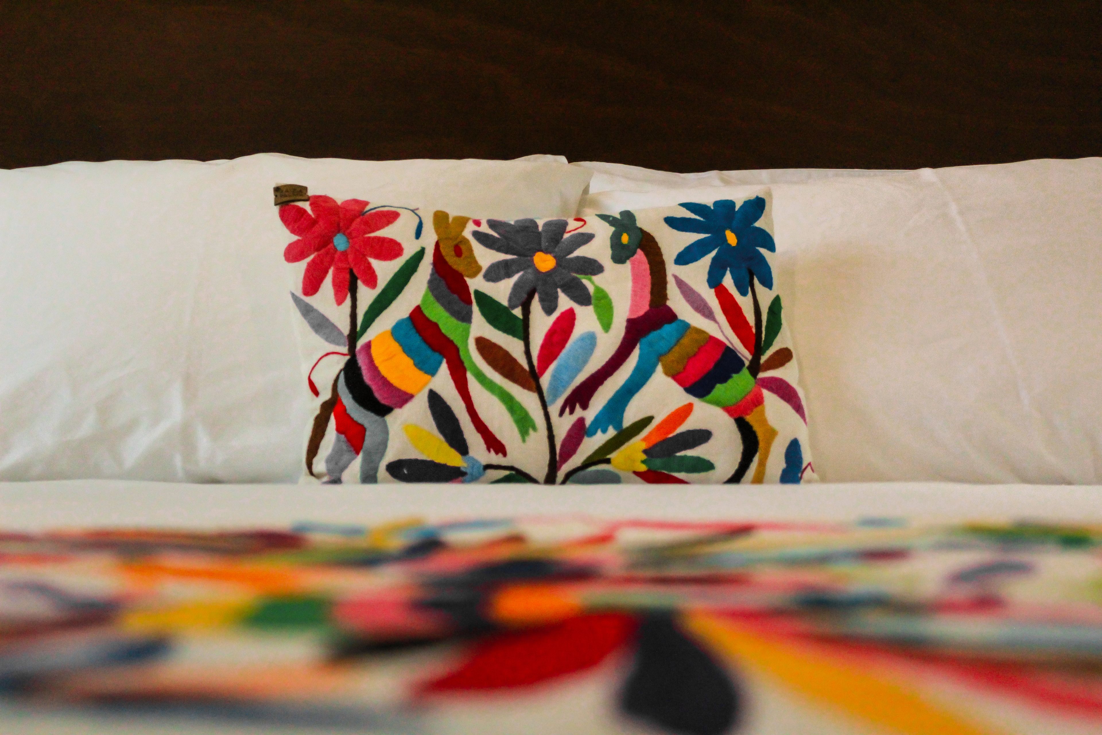 A bed with a colorful pillow featuring floral patterns.