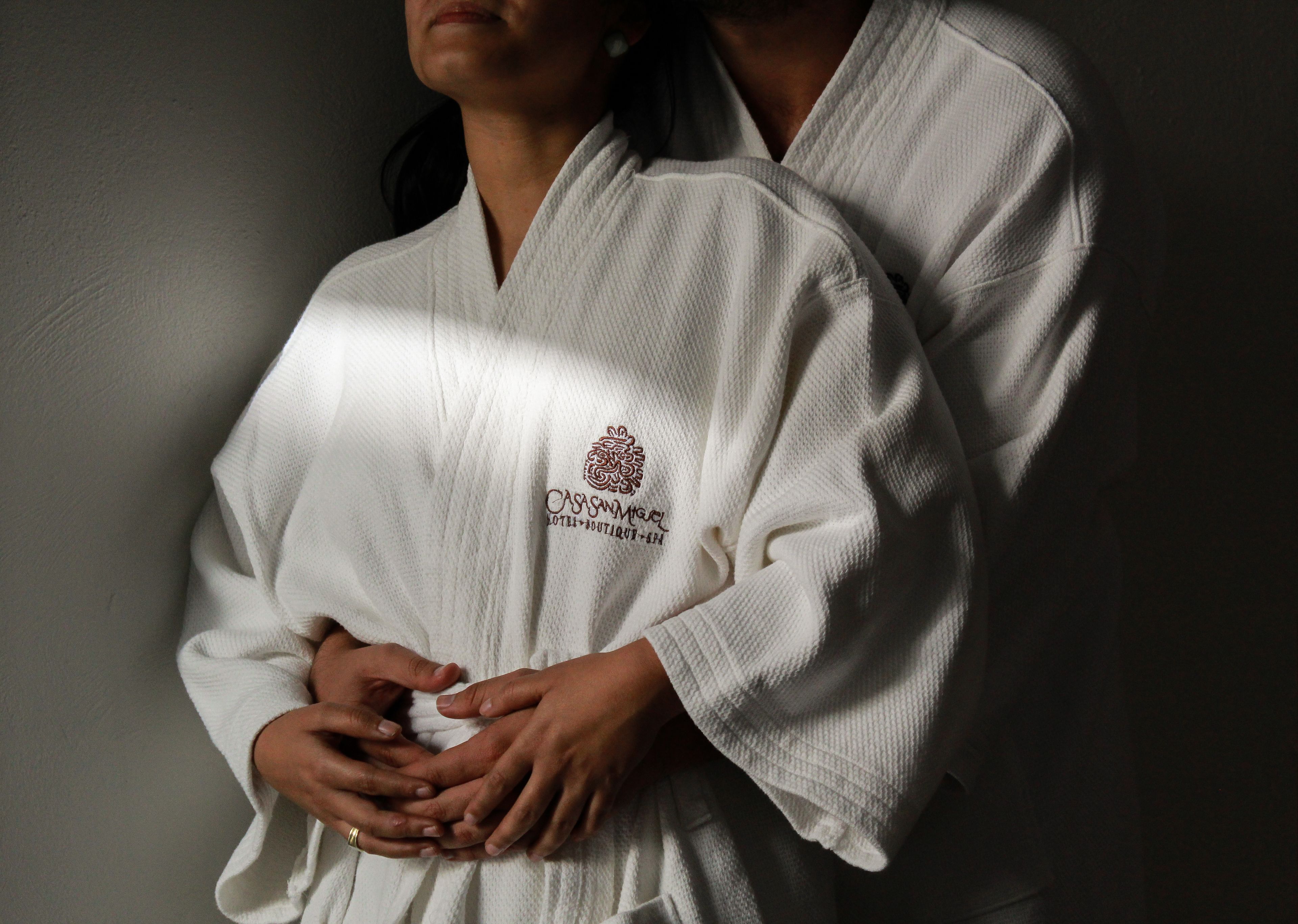 Two individuals in white robes with a logo on the chest.