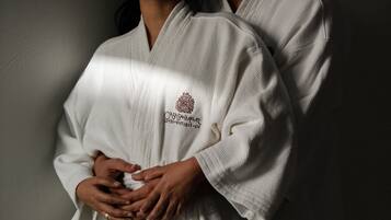 Two individuals in white robes with a logo on the chest.