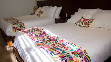 A hotel room with two single beds, each with a colorful floral bedspread and white pillows.