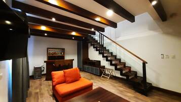 A modern living room with a sofa, a coffee table, a staircase, and a bar area.