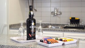 En køkkenbordplade med en Porto Cruz Tawny vinflaske, to tomme vinglas og en bakke med forskelligt snacks.