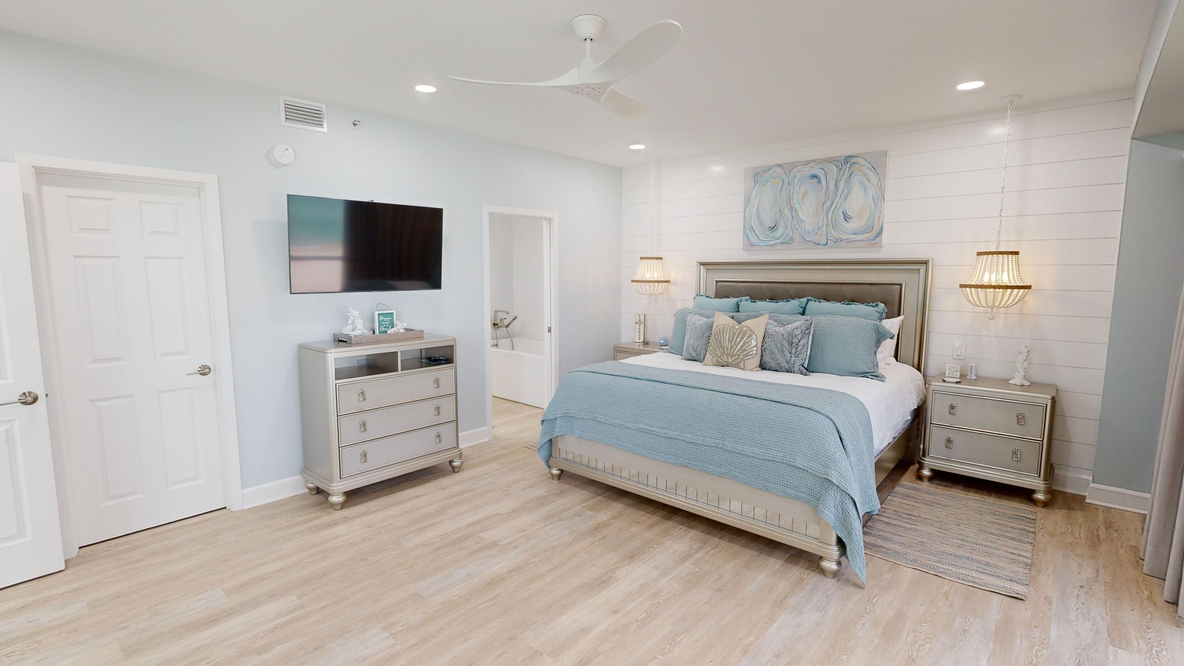 A bedroom with a bed, nightstands, a dresser, a TV, and a ceiling fan.