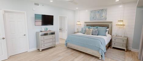 A bedroom with a bed, nightstands, a dresser, a TV, and a ceiling fan.