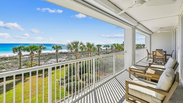 Ein Balkon mit Blick auf den Strand, einem Deckenventilator und Gartenmöbeln.