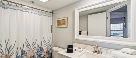 Un baño con inodoro, lavamanos y cortina de ducha con motivos marinos.