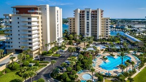 Ein Hochhaus-Hotel mit zahlreichen Balkonen, einem zentral gelegenen Swimmingpool und einer Marina im Hintergrund.
