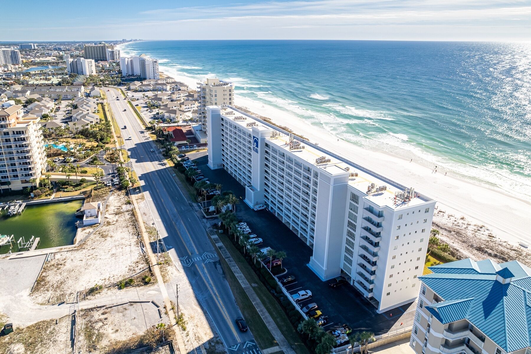A high-rise hotel with multiple floors, located adjacent to a beach.