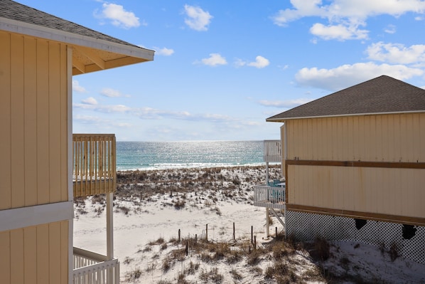 A beach view with a wooden building and a white fence.