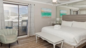 Un dormitorio con una cama grande, un banco, una silla y vistas a un balcón con mobiliario exterior.