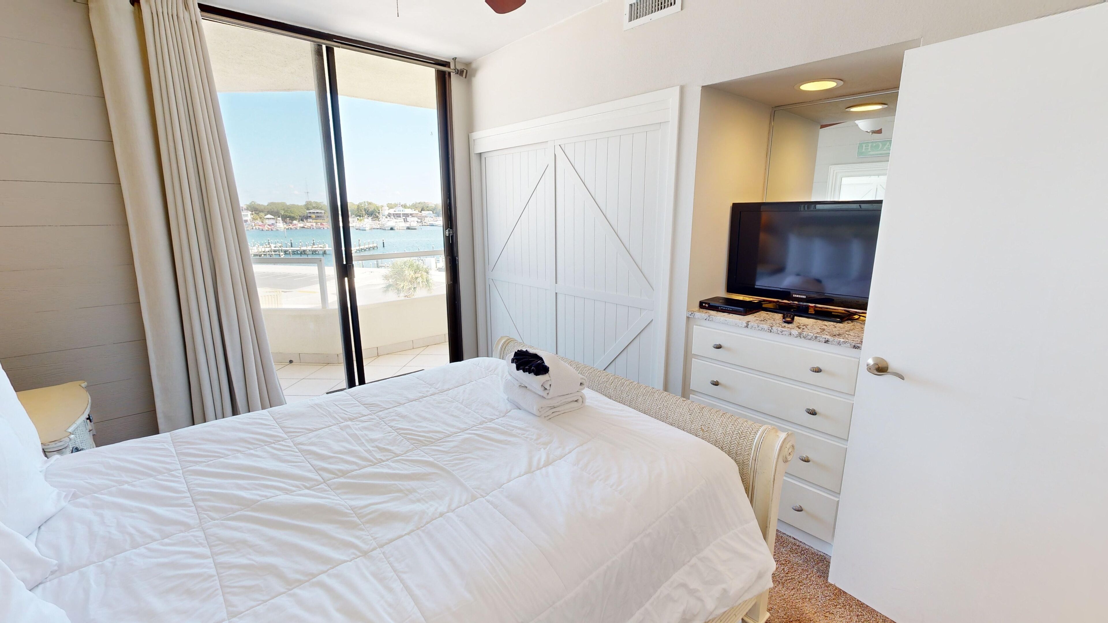 A hotel room with a bed, a television, and a view of the sea.
