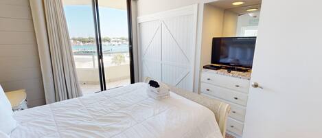 A hotel room with a bed, a television, and a view of the sea.