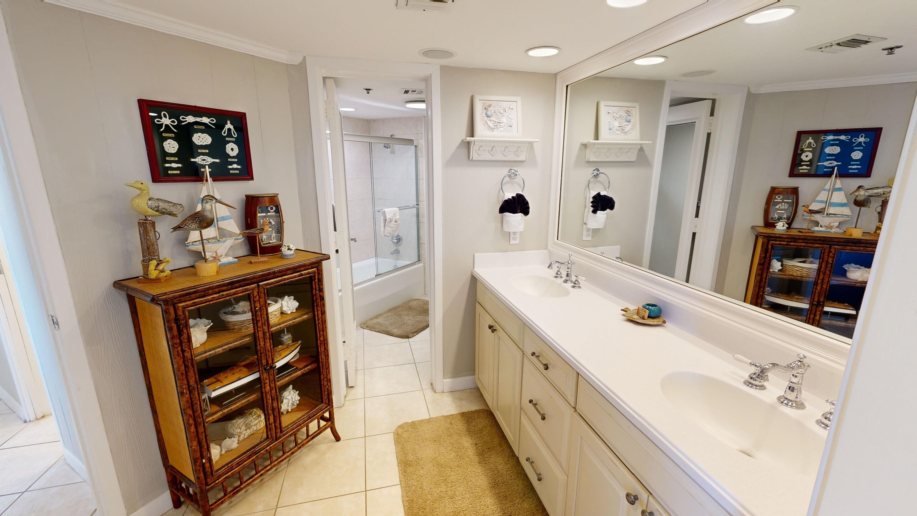 Une salle de bain dotée d’un grand miroir, d’un meuble en bois avec des portes en verre, d’une baignoire et d’un espace douche.