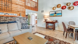 A spacious living area with a high ceiling, a wooden staircase, a dining table with chairs, and a fireplace. - The Other Castle 5 Bedroom Home by RedAwning (Destin)