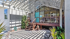 A covered outdoor area with a wooden staircase leading to a balcony. - The Other Castle 5 Bedroom Home by RedAwning (Destin)