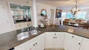 A modern kitchen with granite countertops, stainless steel sinks, and white cabinetry. - Inlet Reef 205 2 Bedroom Apts by RedAwning (Destin)