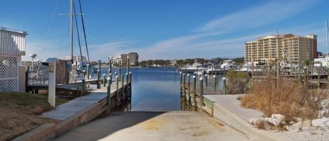 A marina with a concrete walkway leading to the water, surrounded by buildings and boats.