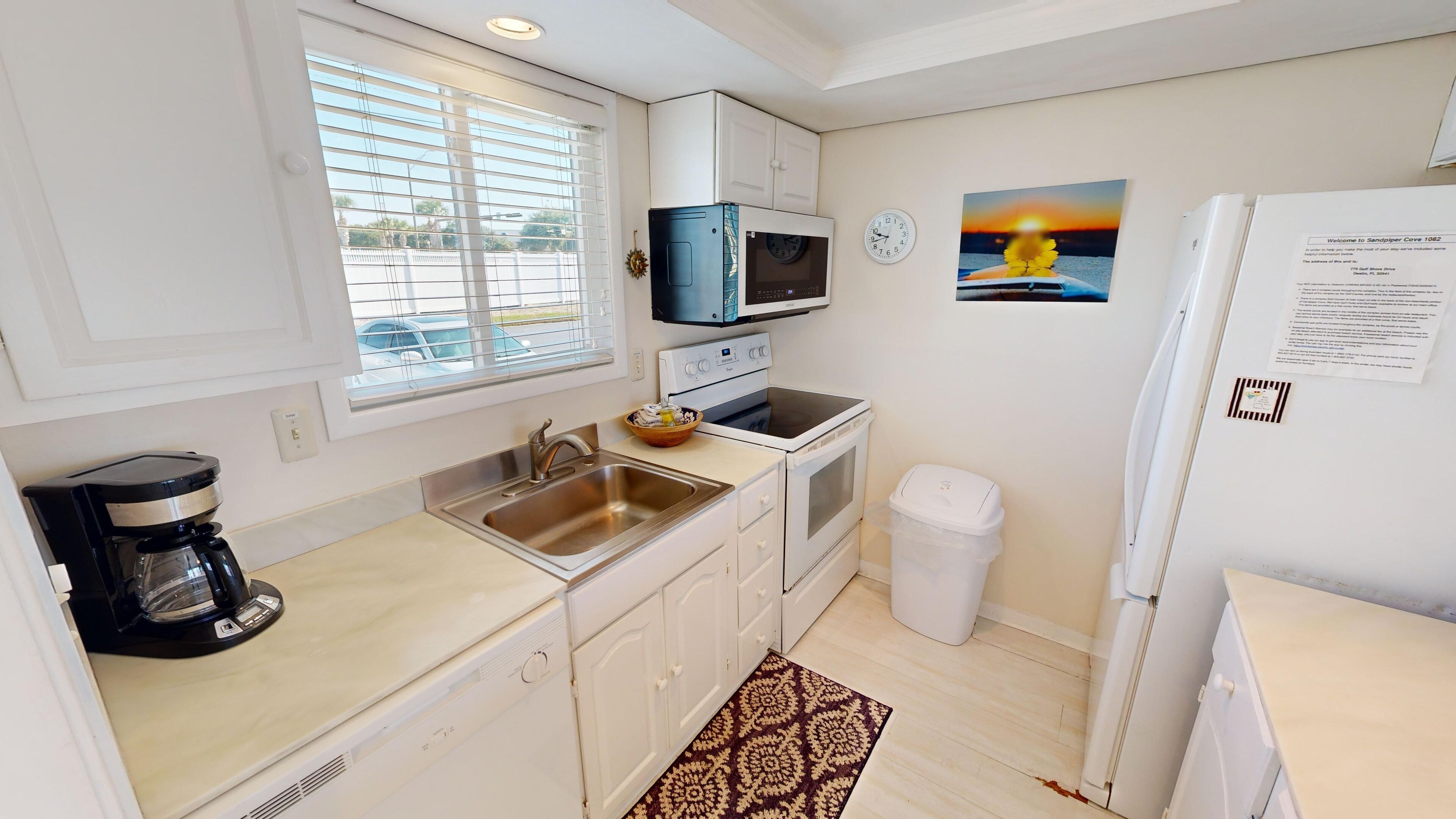 A compact kitchen with a sink, stove, microwave, and refrigerator.