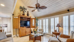 A spacious living room with a glass coffee table, comfortable seating, a wooden entertainment center, and a ceiling fan. - Sandpiper Cove 0012 3 Bedroom Villa by RedAwning (Destin)