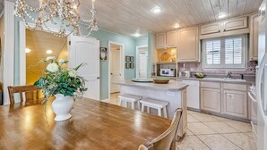 A kitchen with white cabinets, a wooden dining table, and a chandelier. - Sandpiper Cove 0012 3 Bedroom Villa by RedAwning (Destin)