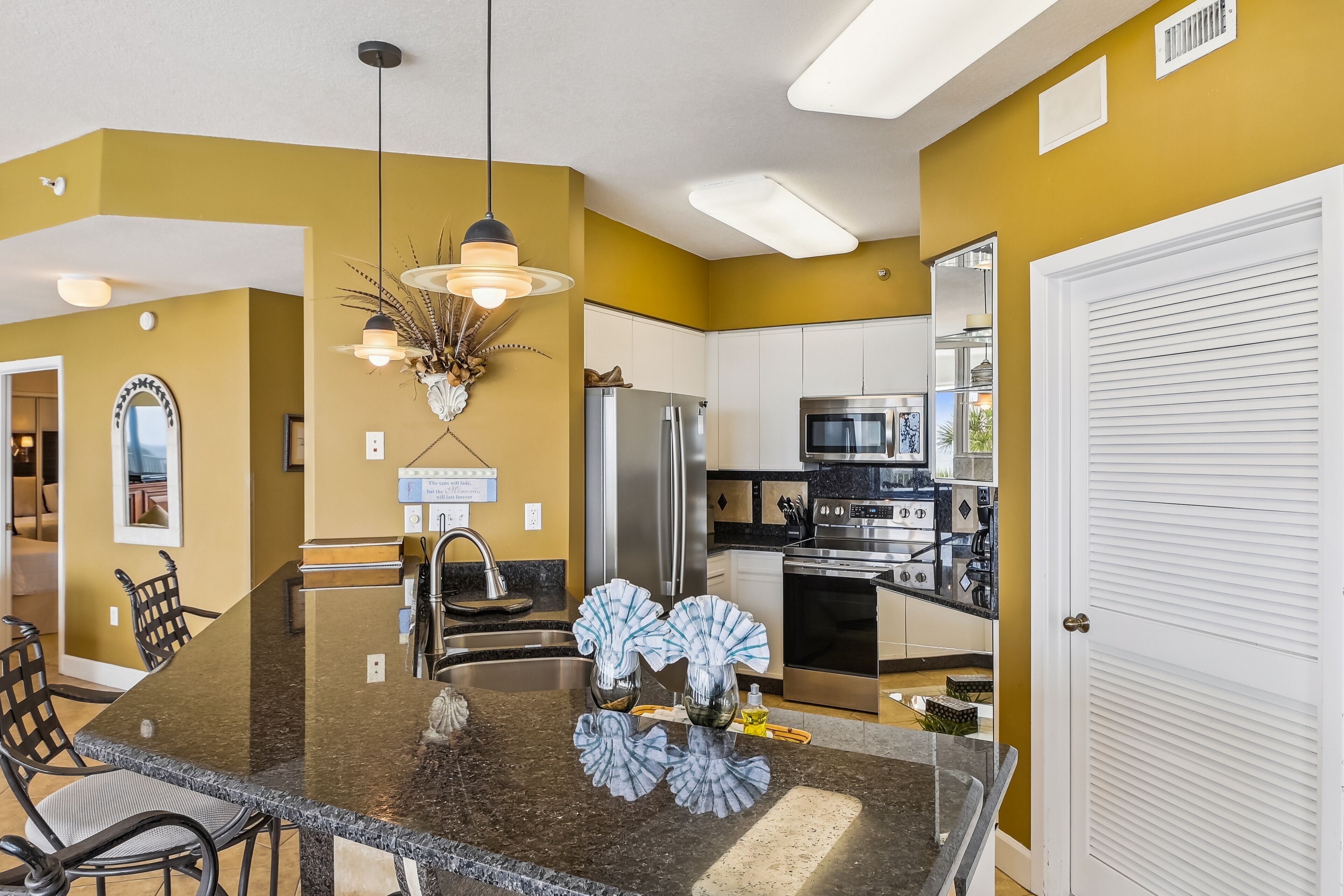 A modern kitchen with granite countertops, stainless steel appliances, and a dining area with a marble table and chairs.