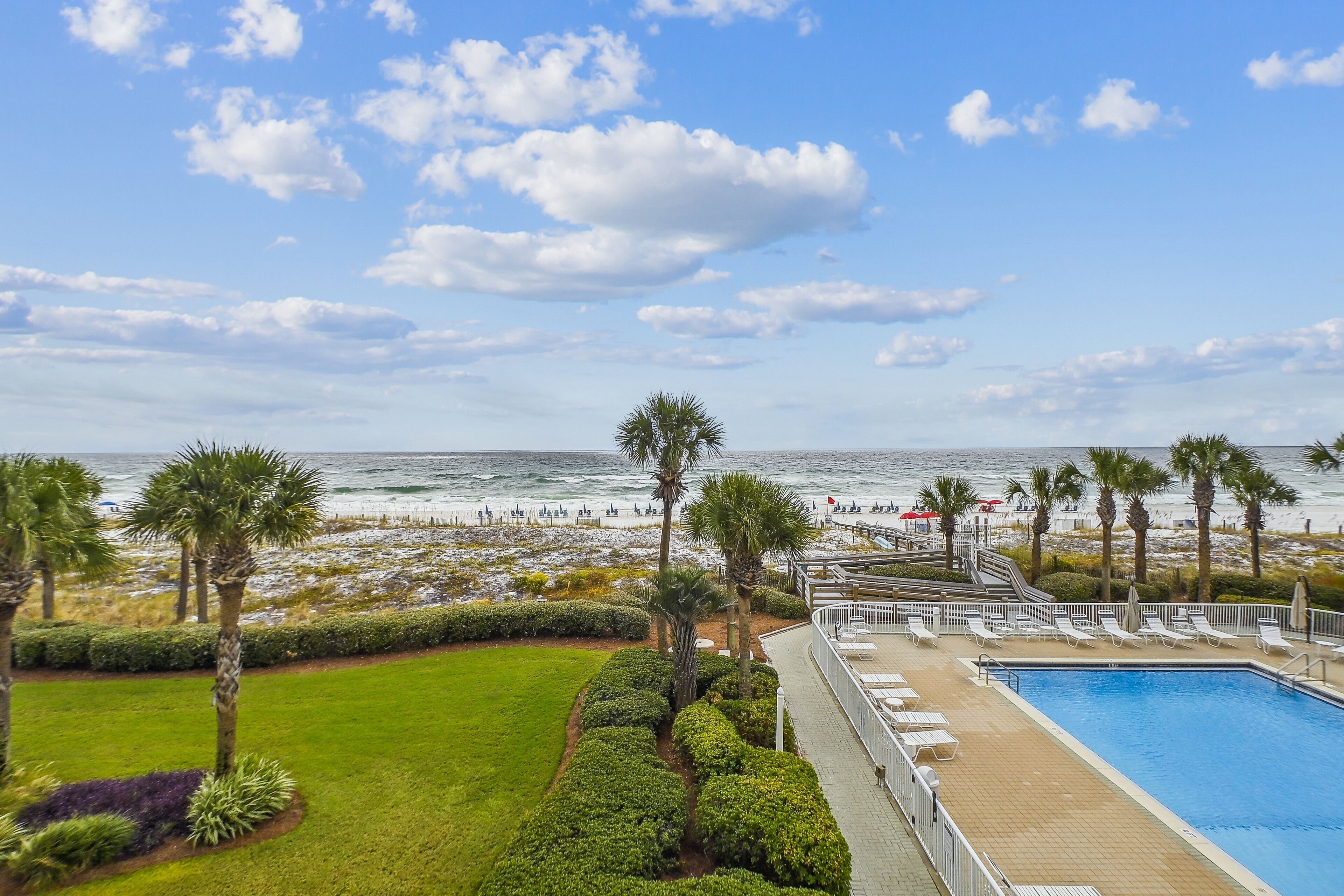 A pool area with a view of the beach and ocean.