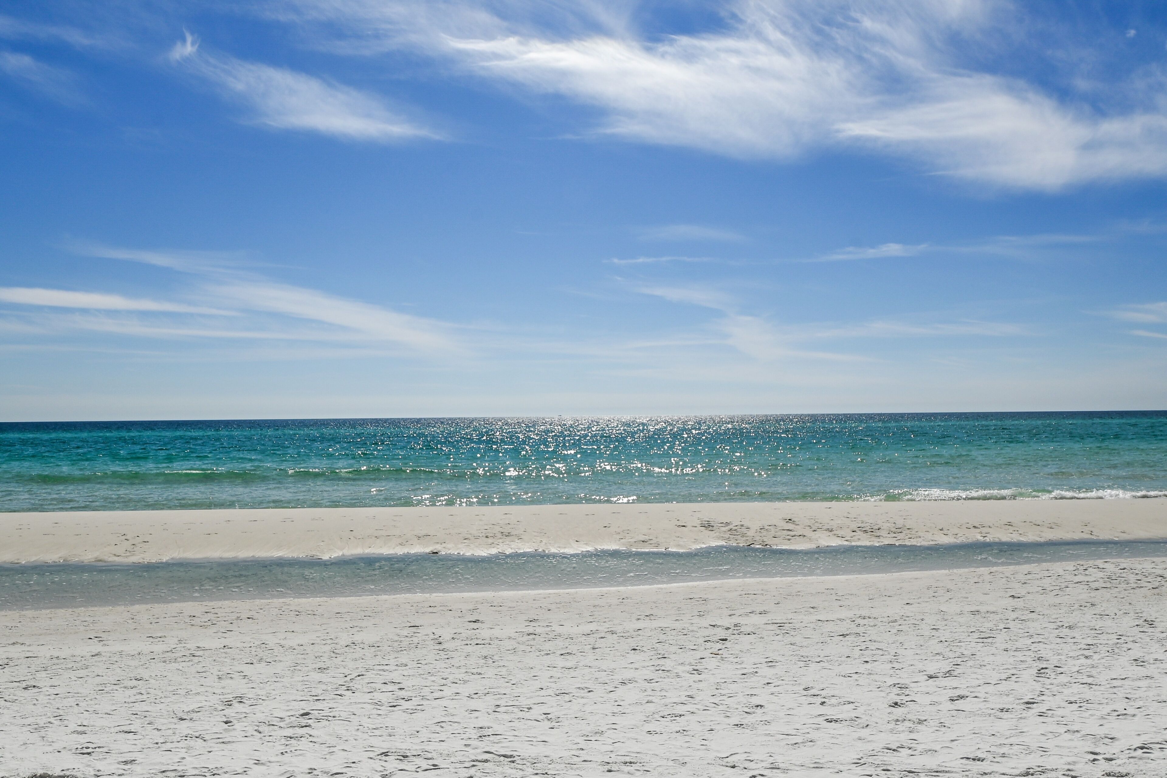 Una playa con cielos despejados y aguas tranquilas.