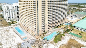 A high-rise hotel with multiple balconies, a pool area, and a beach view. - Pelican Beach 1811 1 Bedroom Condo by RedAwning (Destin)